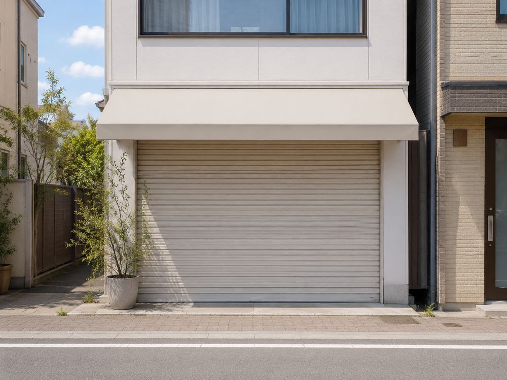 シャッターの下りた1階の店舗。建物は傷んでおらず、脇に鉢植えが置かれている。